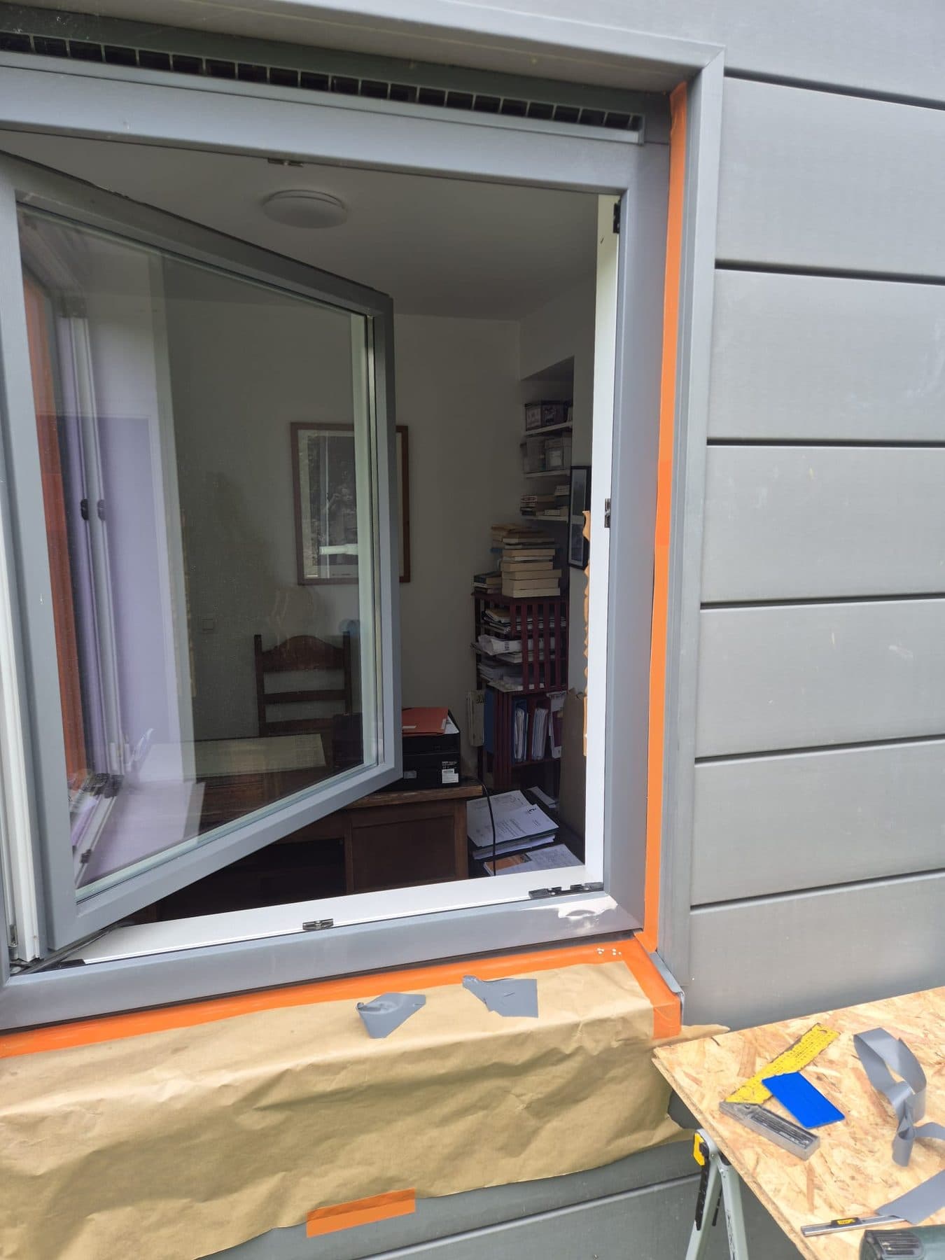 Châssis PVC en cours de pose dans une façade en siding