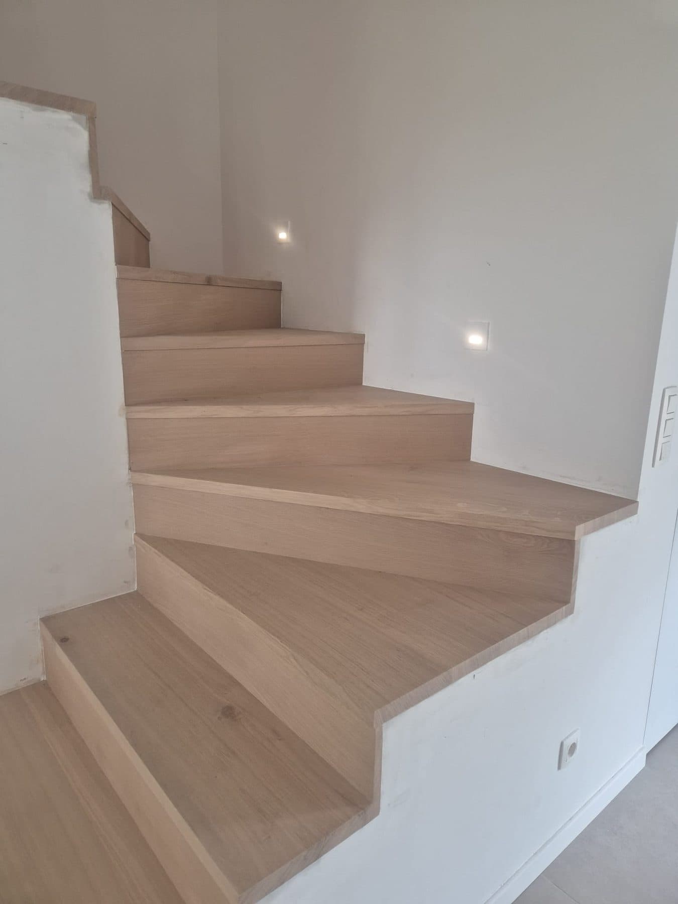 Escalier en chêne à marches balancées, spots encastrés dans le mur de la cage